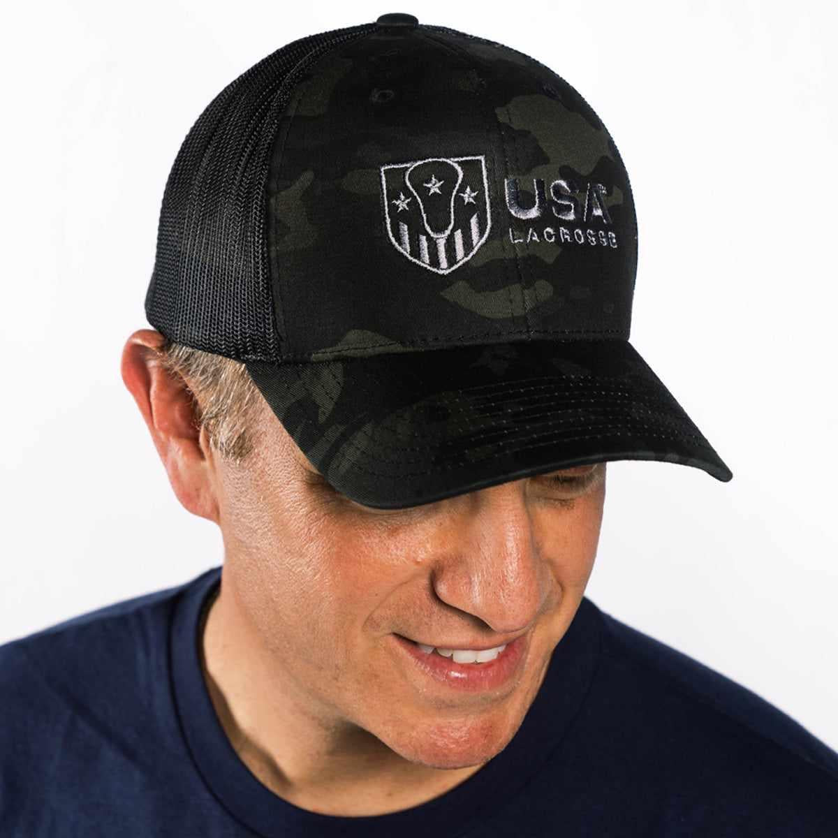Man wearing a black USA Lacrosse cap, smiling.