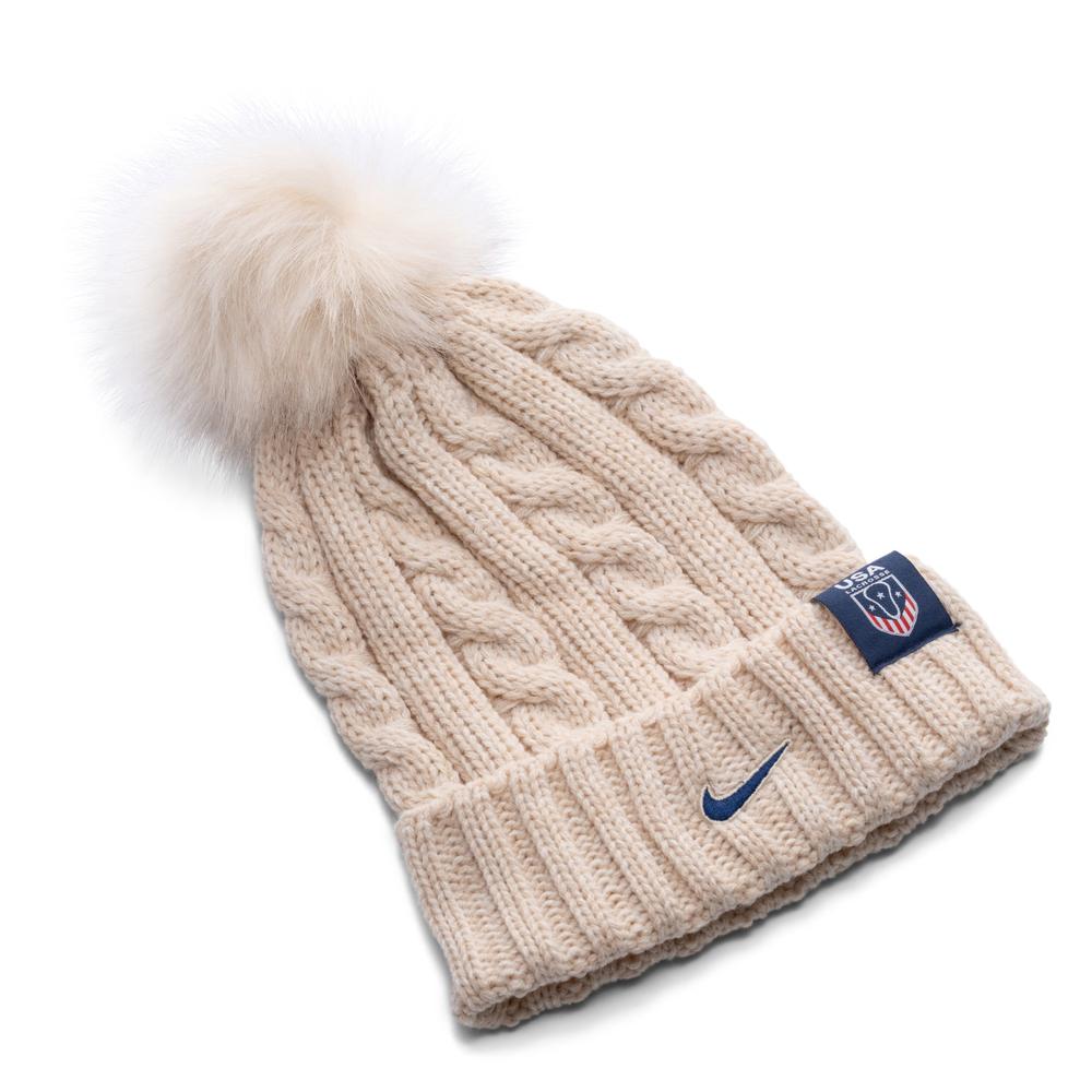 Beige knitted beanie with pom-pom and logo patch.